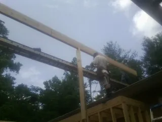 Carpenter setting a ridge beam over a new addition frame — Ice Dam Removal by Roofing Brothers in Belton