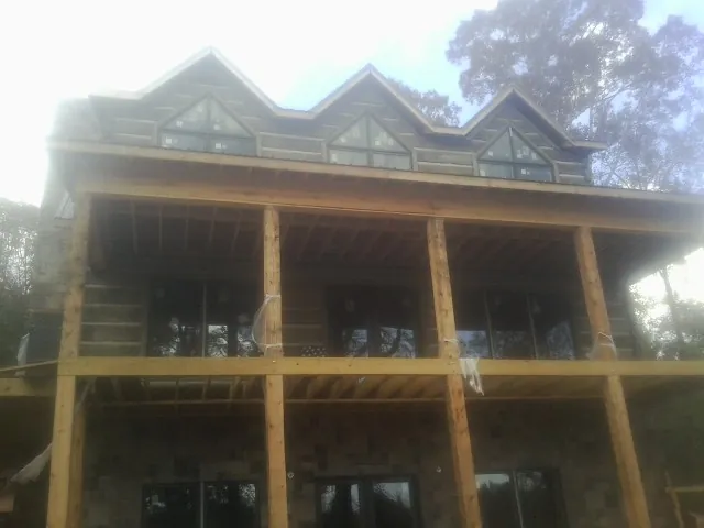 Dormers and porch framing on a large log home under construction — Roof Coating work by our crew in Belton