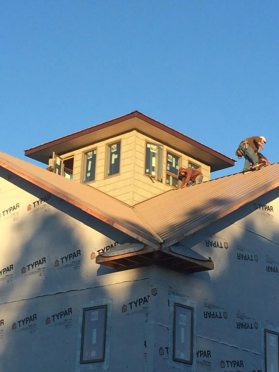 Roofers working around a rooftop cupola on a new metal roof at sunset — Roof Waterproofing in Belton by Roofing Brothers